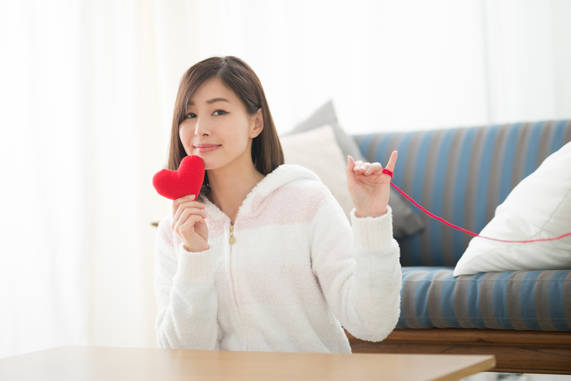 ハートと赤い糸を手にする女性