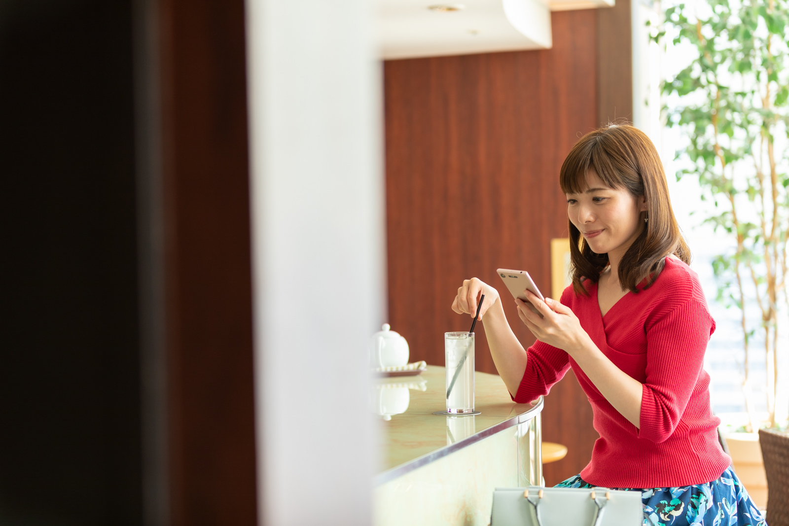 カフェでスマートフォンを見ながらお相手を探す女性